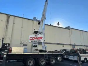 A Coker crane in front of a building with a man standing on the roof.
