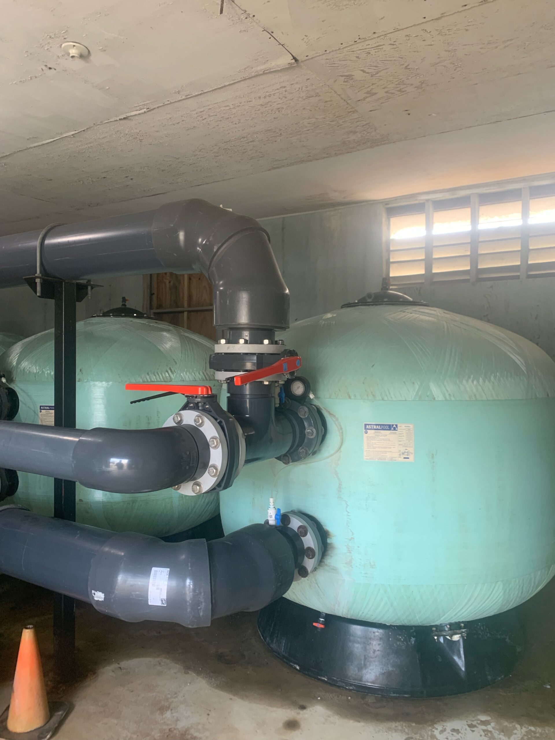 Two large water tanks in a room with pipes.
