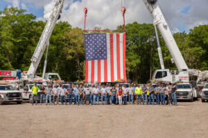 coker crane team in front of cranes and a american flag